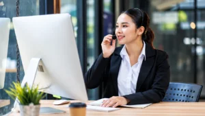 Woman wearing a headset working on a desktop computer in an office.